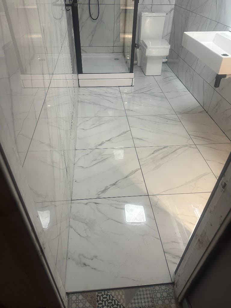 Marble-effect tiled bathroom floor with a shower enclosure and toilet