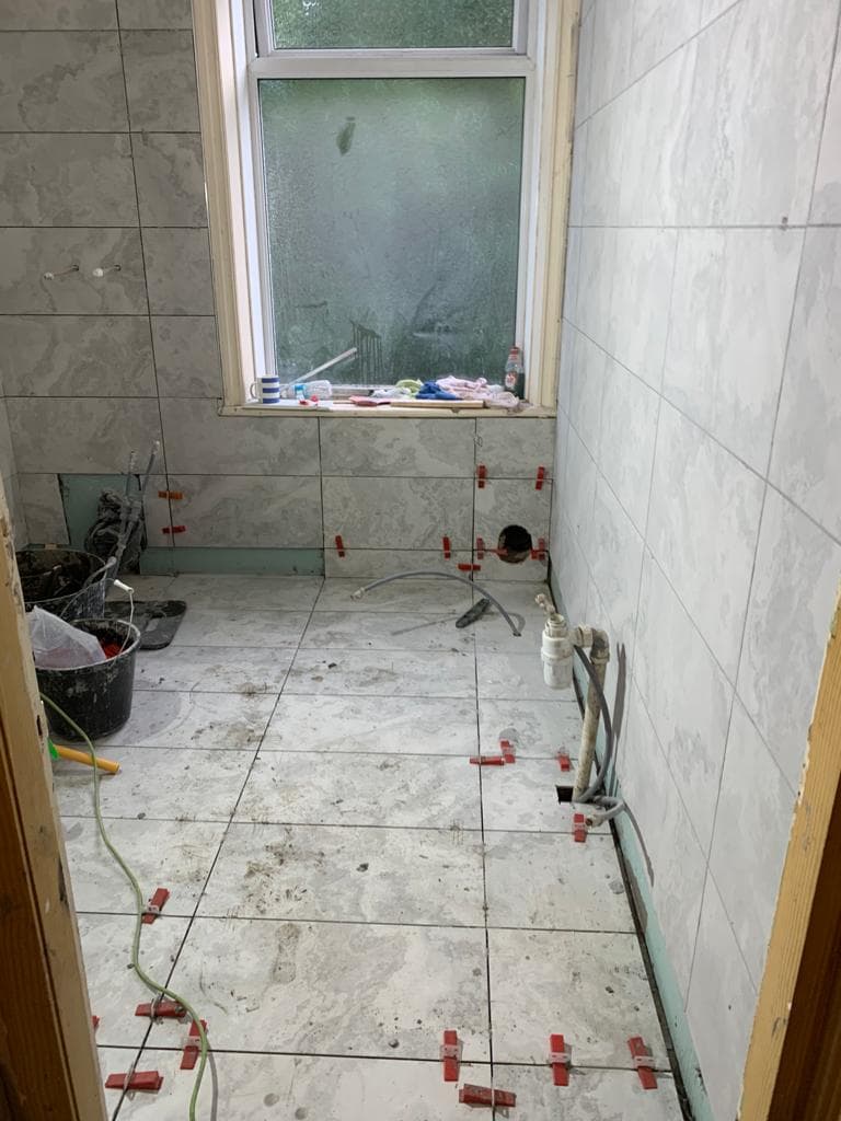 Bathroom tiling in progress, with tile spacers still in place