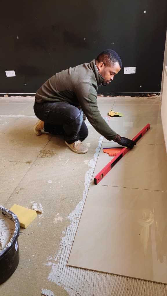 Large-format floor tiles being laid and checked with a spirit level