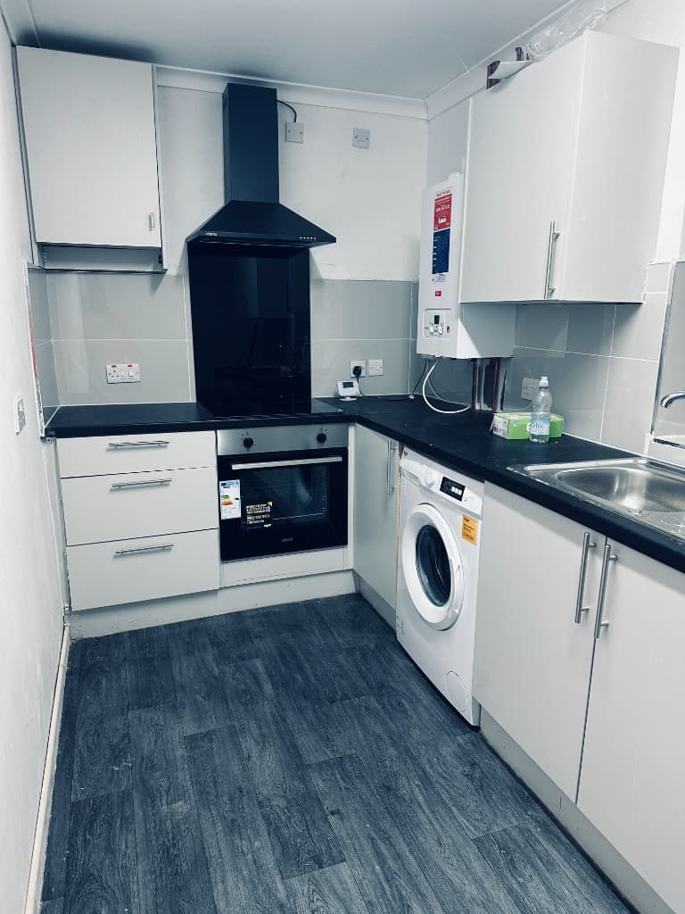 White kitchen with black worktops, oven, hob and integrated laundry space