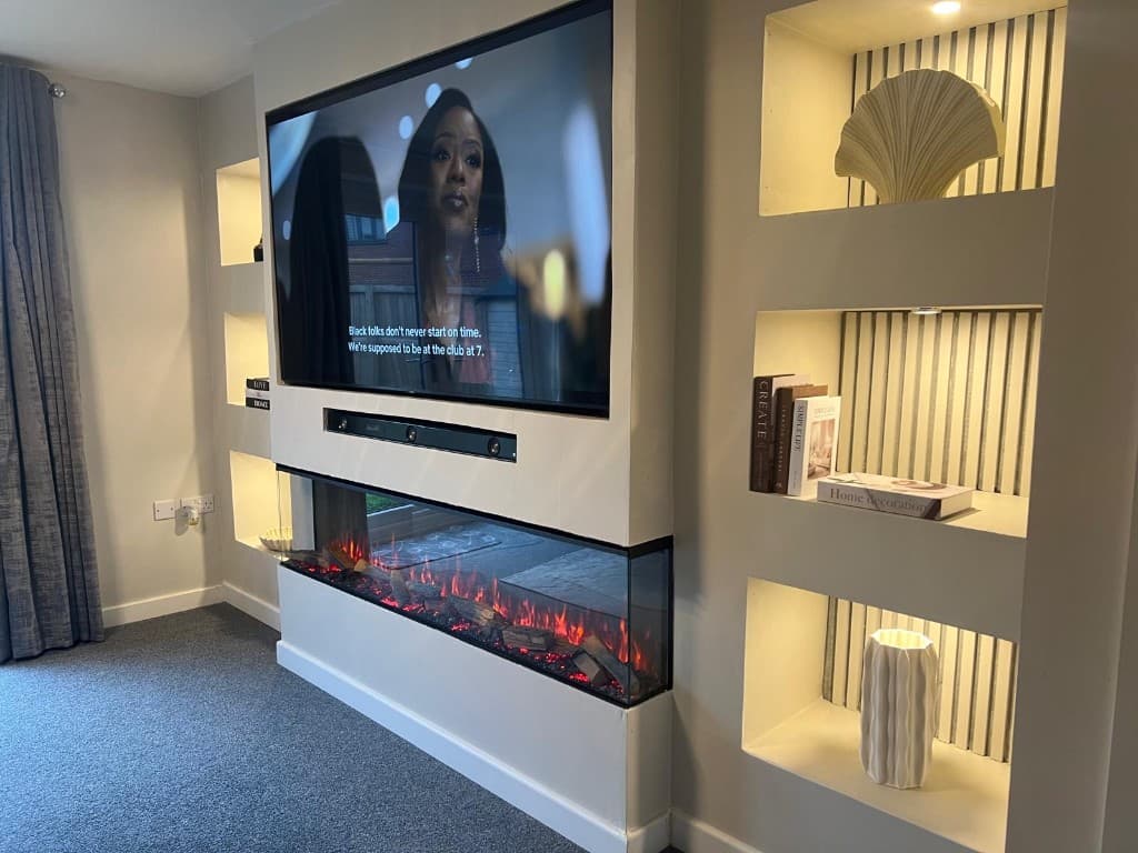 Media wall with a wall-mounted television, electric fire, soundbar and illuminated display niches