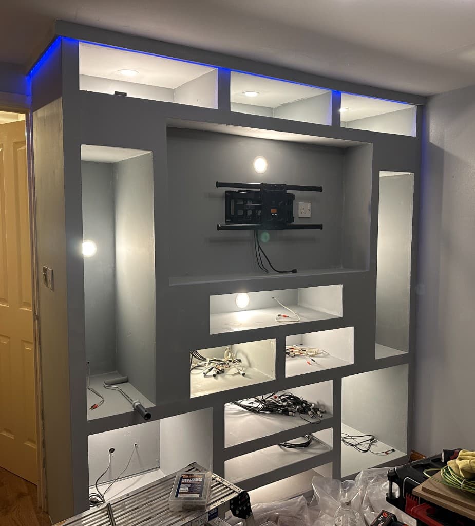 Media wall during installation, with a television mount, lighting and cable routes in place