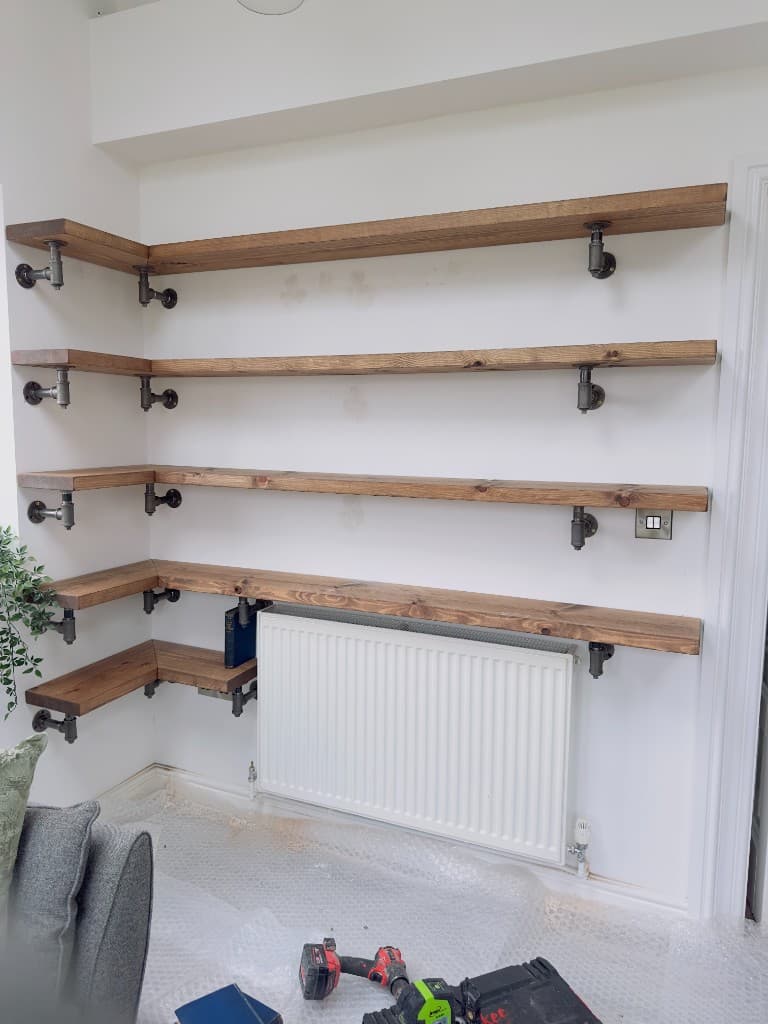 Corner timber shelves on black pipe supports during installation